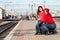 Beautiful mothers with baby and suitcase waiting for train at the station platform. Beautiful train station landscape