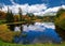 Beautiful mountain lake with a reflection of autum park on water and high peaks in the Background.