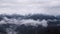 Beautiful mountain landscape with snowy peaks and low clouds. Cloudy low sky overhanging snowy peaks of wooded mountains