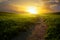 Beautiful mountainous rural landscape Field panorama with dirt road and cloudy sky at sunset