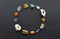 Beautiful multi-colored gems and crystals are arranged in a circle in the form of a rounded frame or wreath on a black contrasting