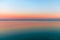 Beautiful multicolor sunset reflected in the waters of Lake Garda, Italy. Skyline. Visible coastline in the evening fog. Winter