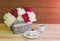 Beautiful multicolored peony flowers in wicker basket, cup of coffee and cake