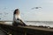 Beautiful multicultural asian woman sits on the waterfront during the surf and gulls around.