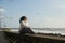 Beautiful multicultural asian woman sits on the waterfront during the surf and gulls around.