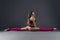 Beautiful muscular woman doing front split. Hanumanasana on a gray background