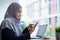 Beautiful Muslim woma talking on the phone and using a computer on her desk