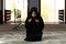 Beautiful Muslim woman in a black dress with hijab praying in a mosque.