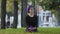 Beautiful muslim young islamic girl in purple hijab female buddhist sits on green grass lawn in city park outdoors