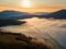 Beautiful mystery landscape with sunset sky and foggy forest between mountains hills.