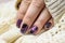 Beautiful nail polish in hand, purple nail art manicure, white background