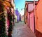 A beautiful narrow brick road full of old colourful homes and flowers in Burano, Italy, an island outside of Venice.