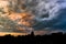 Beautiful natural evening landscape panorama. Silhouette roofs of houses and trees. Hembic clouds at sunset, bright
