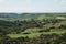 A beautiful natural landscape with green trees on a hilly terrain against a blue sky.