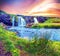 Beautiful natural magical scenery with a waterfall Kirkjufell and yellow flowersat dawn in Iceland. Exotic countries. Amazing