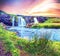 Beautiful natural magical scenery with a waterfall Kirkjufell and yellow flowersat dawn in Iceland. Exotic countries. Amazing