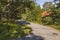 Beautiful nature landscape view. Bendy country road and roofs of houses between green trees