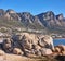 Beautiful, nature view of the beach front or rocky boulder on the seashore against a mountain landscape and blue sky on