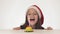 Beautiful naughty girl teenager in a Santa Claus hat blows out a candle on a festive cake on white background