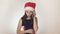 Beautiful naughty girl teenager in a Santa Claus hat emotionally communicates on the smartphone on white background