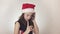 Beautiful naughty girl teenager in a Santa Claus hat emotionally communicates on the smartphone on white background