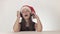 Beautiful naughty girl teenager in a Santa Claus hat listens to music on headphones and sings along on white background