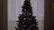 Beautiful New Year decorated tree with glowing colorful lights, green shiny Christmas fir with garland, stars and