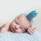 Beautiful newborn baby girl in blue crown, closeup portrait