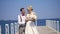 Beautiful newlywed couple, bride and groom dancing outdoors, on a beautiful pier, against the blue sea and sky. summer