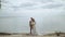 Beautiful newlywed couple posing to camera and lean their heads together, the sea is in the background, slow motion.