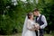 Beautiful newlyweds couple walking in the woods. Honeymooners. Bride and groom holding hand in pine forest