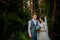 Beautiful newlyweds couple walking in the woods. Honeymooners. Bride and groom holding hand in pine forest, photo for Valentine`s