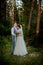 Beautiful newlyweds couple walking in the woods. Honeymooners. Bride and groom holding hand in pine forest, photo for Valentine`s