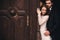 Beautiful newlyweds hugging near the ancient door. Wedding portrait of a stylish groom and a young bride near old house in in a