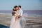 Beautiful newlyweds on the sea shore and gentle groom, touching the bride`s hair. front view.