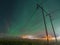Beautiful night Aurora over double wooden pole power lines and electrical substation in autumn field, side view, starry sky with