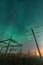 Beautiful night Aurora over single wooden pole power lines and electrical substation in autumn field, side view, vertical photo of