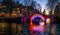 Beautiful night city canals of Amsterdam with moving passenger boat.