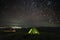 Beautiful night landscape, tent and star trails in the sky and city lights in Ukraine