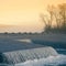 A beautiful Norwegian autumn scenery. Misty morning on a lake. Water flowing over the dam, waterfall.