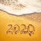 Beautiful Numbers 2020 year handwritten on sandy beach background