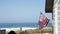 A beautiful oceanfront property with a classic American flag on the side of it with the coastline in the background.