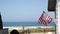 A beautiful oceanfront property with a classic American flag on the side of it with the coastline in the background.