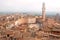 Beautiful old buildings under morning mist in Siena, Tuscany. Tile roofs and 14th century tower Torre del Mangia, Italy.