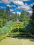 Beautiful old green abbey monastery garden park in summer, holy heart of jesus statue on hill, boxwood hedges forming latin