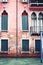 Beautiful old house with Venetian windows, red facade and green shutters near canal, Venice town, Italy, Europe