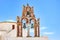 Beautiful old orthodox white church with blue dome and the old arch with bells against the blue sky, Santorini, Greece, Europe.