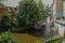 A beautiful old pleasure boat with tourists floats along a river canal in a beautiful city with trees and houses along the bridges