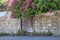 Beautiful, old weathered wooden door set in an old stone wall, framed in purple bougainvillea.