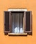 Beautiful old window frame with brown wooden shutters and bright yellow wall. Rural or antique window frame. Design element.